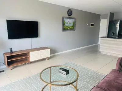 a living room with a tv and a glass table at Minimalist 2 bed 1 full bathroom in Cape Town