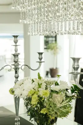 a vase of flowers sitting on a table under a chandelier at Beach House in Sunset Beach in Cape Town