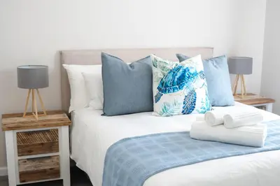 a bedroom with a bed with blue and white pillows at Manchester Heights Deluxe Apartments in Cape Town
