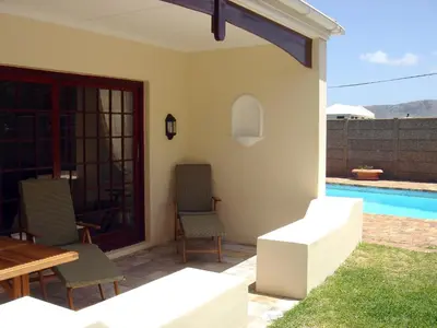 a patio with a table and chairs and a pool at Milkwood Lodge in Hermanus
