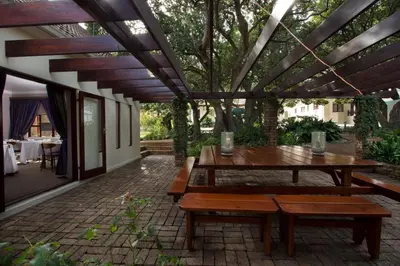 a patio with a wooden table and benches at Milkwood Lodge in Hermanus