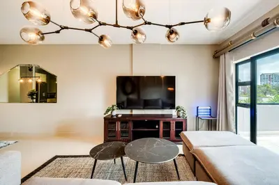 a living room with a tv and a table at Belina - Knightsbridge Prestige Suite in Cape Town