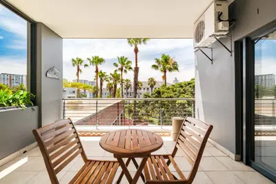 a balcony with a table and chairs and palm trees at Belina - Knightsbridge Prestige Suite in Cape Town
