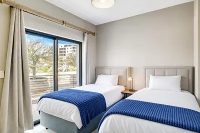 two beds in a room with a window at Belina - Knightsbridge Prestige Suite in Cape Town