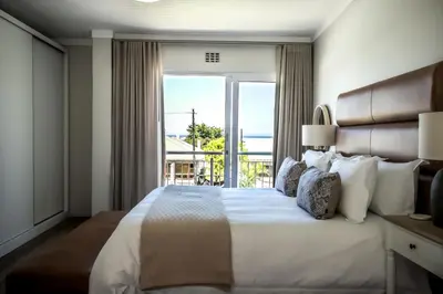 a bedroom with a large bed with a large window at Tide & Together in Hermanus