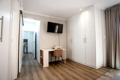 a white room with a desk and a tv on the wall at Tide & Together in Hermanus