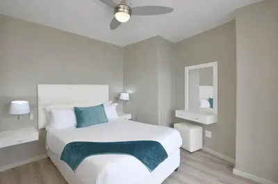 a bedroom with a white bed with blue pillows at Luxury Beachside Apartment in Aquarius in Cape Town