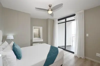 a bedroom with a bed and a ceiling fan at Luxury Beachside Apartment in Aquarius in Cape Town