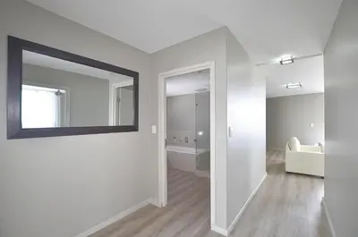a white room with a mirror and a bathroom at Luxury Beachside Apartment in Aquarius in Cape Town