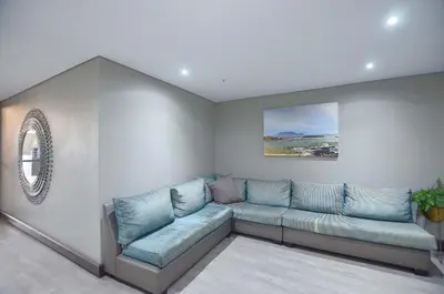 a living room with a blue couch in a room at Luxury Beachside Apartment in Aquarius in Cape Town