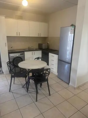 a kitchen with a table and chairs and a refrigerator at Stepney Apartment in Cape Town