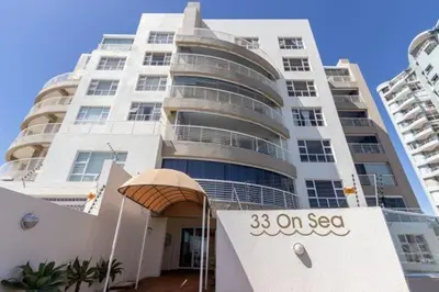 a tall white building with a sign in front of it at Luxury Beach Front Apartment in Strand