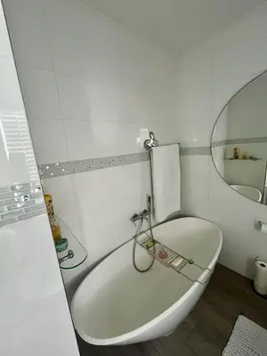 a white bathroom with a tub and a mirror at Luxury Beach Front Apartment in Strand
