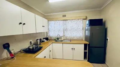 a kitchen with white cabinets and a black refrigerator at Casa Kari in Brackenfell