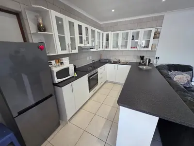 a kitchen with white cabinets and a black counter top at Alvera in Strand