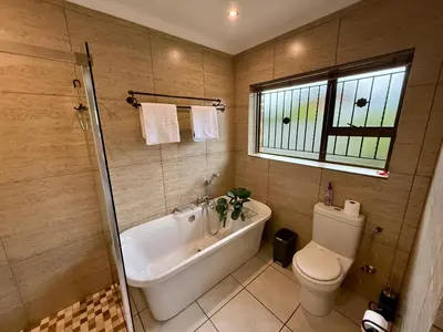 a bathroom with a tub and a toilet and a window at Welcome Home in Somerset West