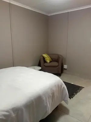 a bedroom with a white bed and a chair at Home in Brooklyn Cape Town in Cape Town
