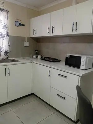 a kitchen with white cabinets and a microwave at Home in Brooklyn Cape Town in Cape Town