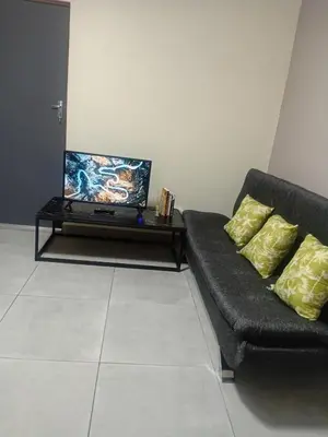 a living room with a couch and a flat screen tv at Home in Brooklyn Cape Town in Cape Town