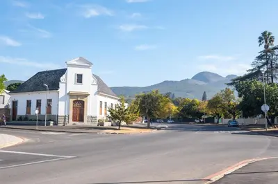 a white church on a street with mountains in the background at 113 Paarl 2 Bedroom Lux Aprt With Parking & Aircon in Paarl