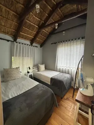 a bedroom with two beds and a window at The Little Thatch Cottage in Greyton