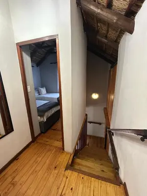 a hallway with a bedroom and a bed in a room at The Little Thatch Cottage in Greyton