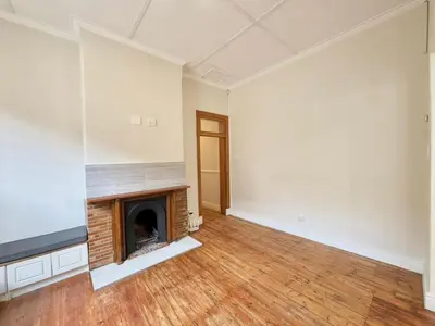 an empty room with a fireplace and wooden floors at 3 Bedroom Vintage Home in Cape Town