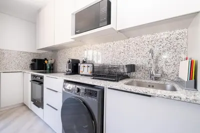 a kitchen with white cabinets and a washer and dryer at 116 Paarl - Lux 1 Bedroom Apt with AC and Parking in Paarl