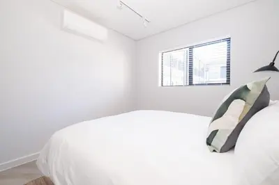 a white bedroom with a bed and a window at 116 Paarl - Lux 1 Bedroom Apt with AC and Parking in Paarl