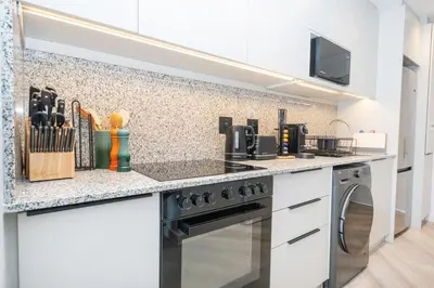 a kitchen with white cabinets and a stove top oven at 213 Paarl 2 Bedroom Lux Aprt With Parking & Aircon in Paarl