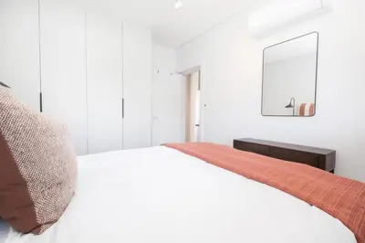 a white bedroom with a bed and a mirror at 216 Paarl Lux 1 Bdrm Apt with Parking and AC in Paarl