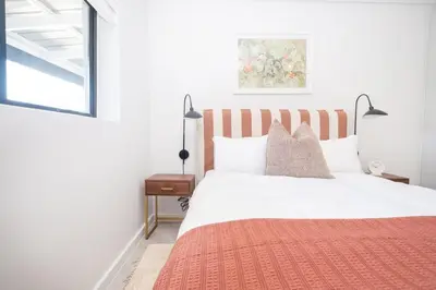 a bedroom with a white bed with a red blanket at 216 Paarl Lux 1 Bdrm Apt with Parking and AC in Paarl