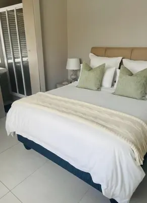 a large white bed with green pillows in a bedroom at Cape Coral in Cape Town