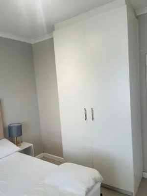 a bedroom with a large white cabinet next to a bed at Cape Coral in Cape Town