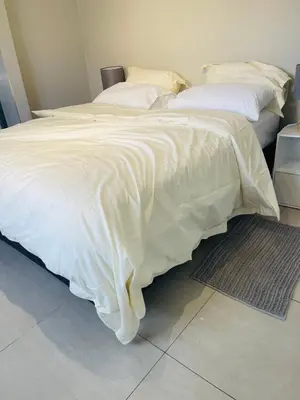 a bedroom with two beds with white sheets and a rug at Cape Coral in Cape Town