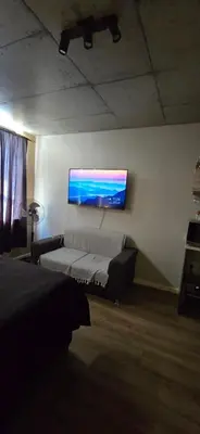 a room with a couch and a tv on a wall at Ebbies place in Cape Town