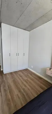an empty room with white cabinets and a wooden floor at Ebbies place in Cape Town