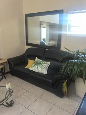 a black leather couch in a living room with a mirror at 22 on BREEZAND in Cape Town