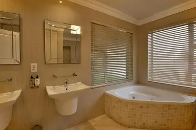 a bathroom with a tub and a sink and a mirror at The Coach House at Val du Charron in Wellington