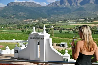 a woman standing next to a white building with mountains in the background at The Coach House at Val du Charron in Wellington