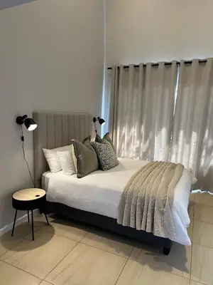 a bed with pillows and a table in a bedroom at Little Nest in Somerset West