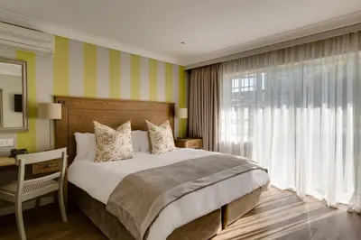 a bedroom with a bed and a desk and a window at Protea Hotel by Marriott Stellenbosch & Conference Centre in Stellenbosch