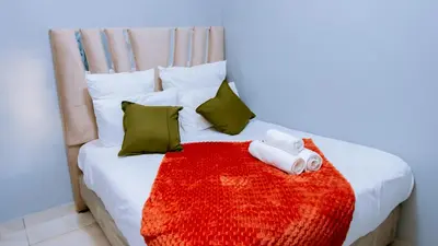 a bed with two rolled towels on a red blanket at DC Guest House in Avondale