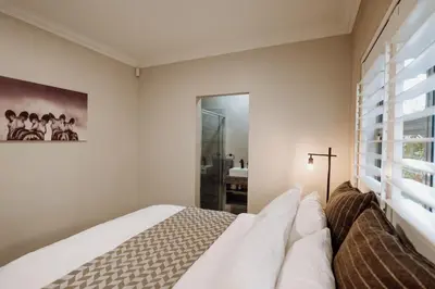 a white bedroom with a bed and a window at Coats Haven in Hermanus
