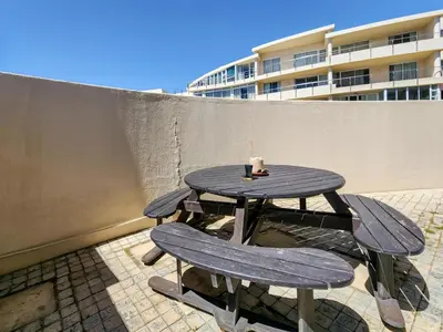 a picnic table with two chairs and a candle on it at Seaside Serenity with Ocean View in Cape Town