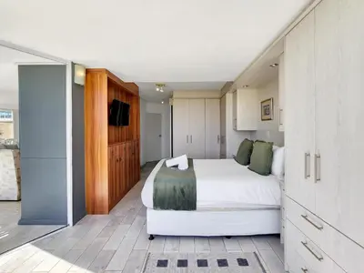 a bedroom with a large white bed and a tv at Seaside Serenity with Ocean View in Cape Town