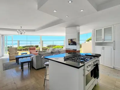 a kitchen with a stove and a living room at Seaside Serenity with Ocean View in Cape Town