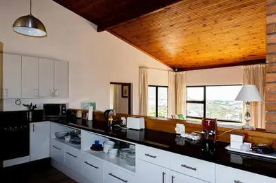 a kitchen with white cabinets and a black counter top at Hillside View in Pringle Bay