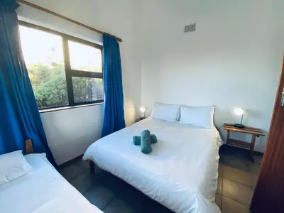 two beds in a room with a teddy bear on the bed at Hillside View in Pringle Bay