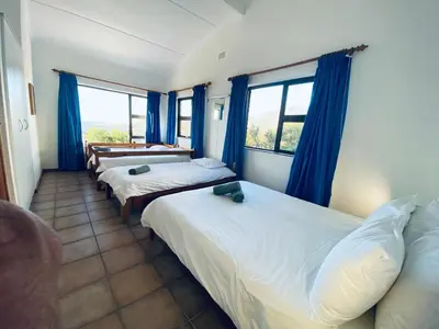 a room with three beds with blue curtains at Hillside View in Pringle Bay